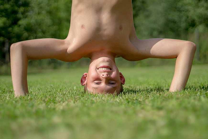 Happy Boy Doing Headstand on Green Grass in Park