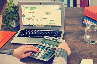Woman using calculator and laptop for accounting work
