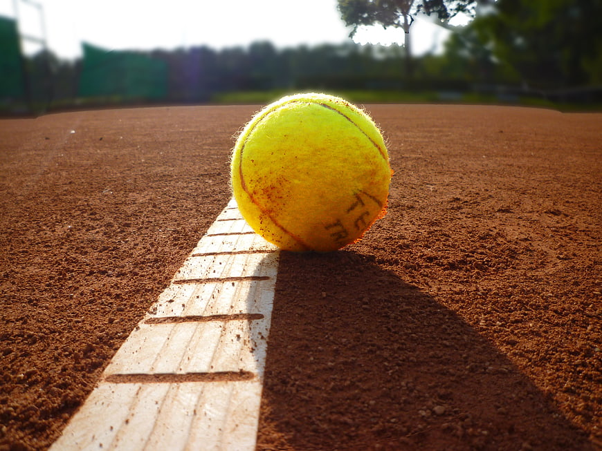 Tennis ball resting on white line of a clay court