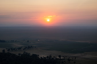 Sunset over vast savanna landscape with distant mountains