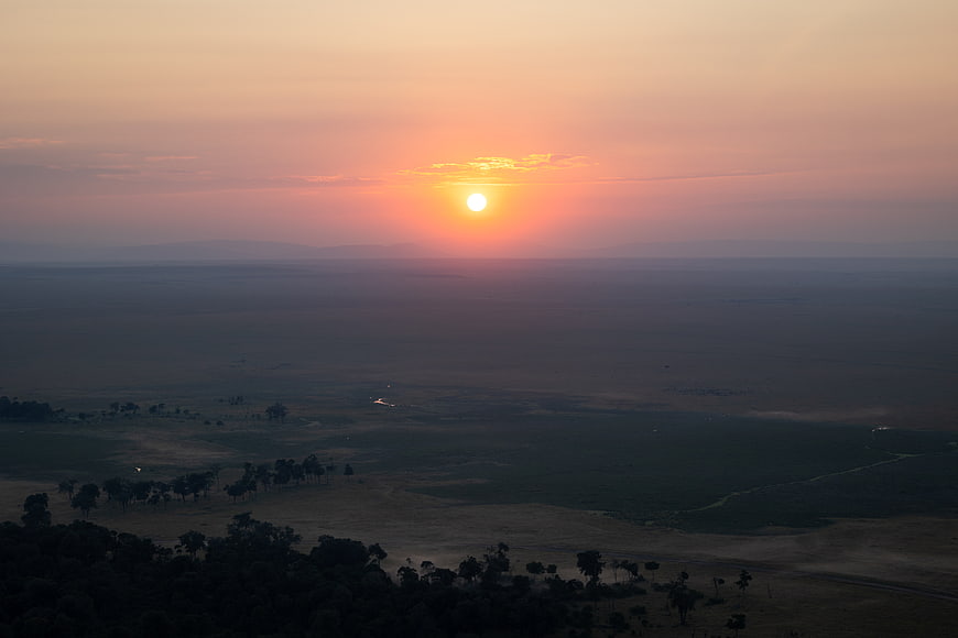 Sunset over vast savanna landscape with distant mountains