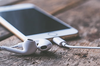 White Earphones and Smartphone on Rustic Wooden Table
