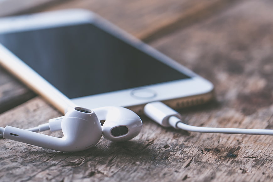 White Earphones and Smartphone on Rustic Wooden Table