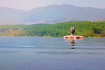 Woman Relaxing in Infinity Pool with Mountain View