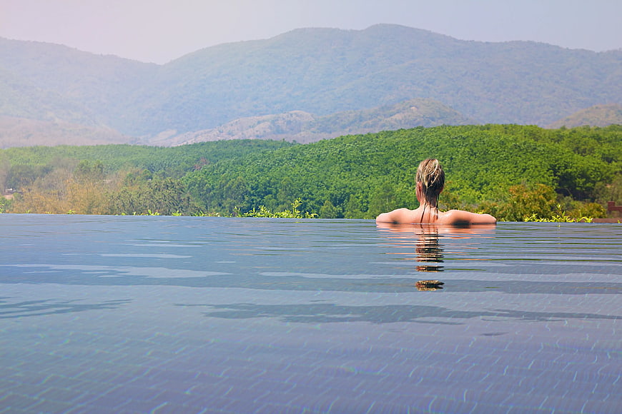 Woman Relaxing in Infinity Pool with Mountain View