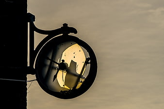 Broken vintage street clock silhouette against sky
