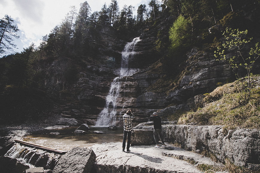 Two Photographers Capturing a Mountain Waterfall in Forest