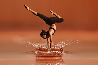 Woman performing handstand in water splash with warm background
