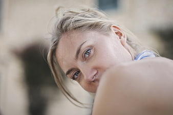 Close-up portrait of blonde woman with blue eyes looking over shoulder