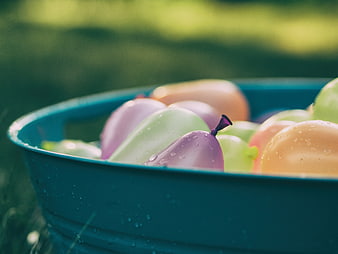 Colorful Water Balloons in Blue Tub with Droplets