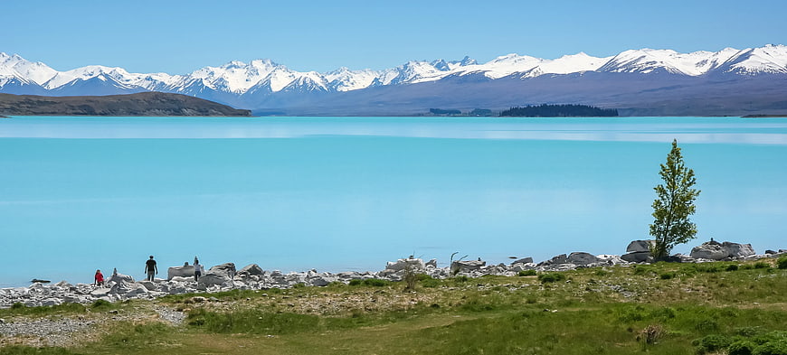 Turquoise Lake with Snow-Capped Mountains and Hikers