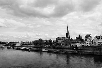Black and white cityscape with river, boats, and church spire