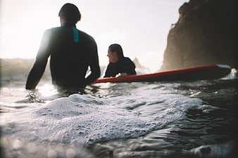 Surfers in Wetsuits Waiting for Waves at Sunset