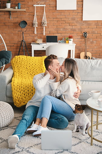 Young couple kissing on living room floor with dog