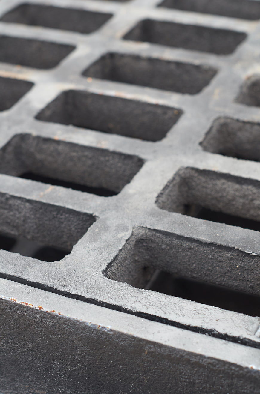 Close-up of black metal drainage grate texture