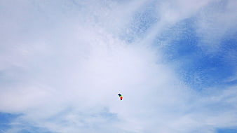 Colorful Parachute Floating in Blue Sky with Clouds