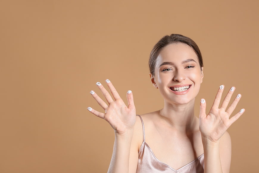 Happy Woman Showing Manicured Hands on Beige Background