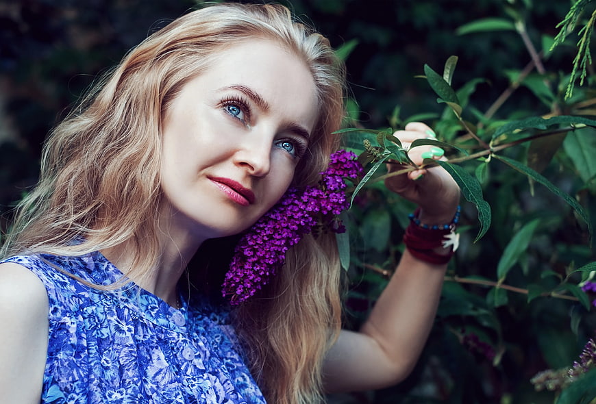 Blonde Woman in Blue Dress Smelling Purple Butterfly Bush