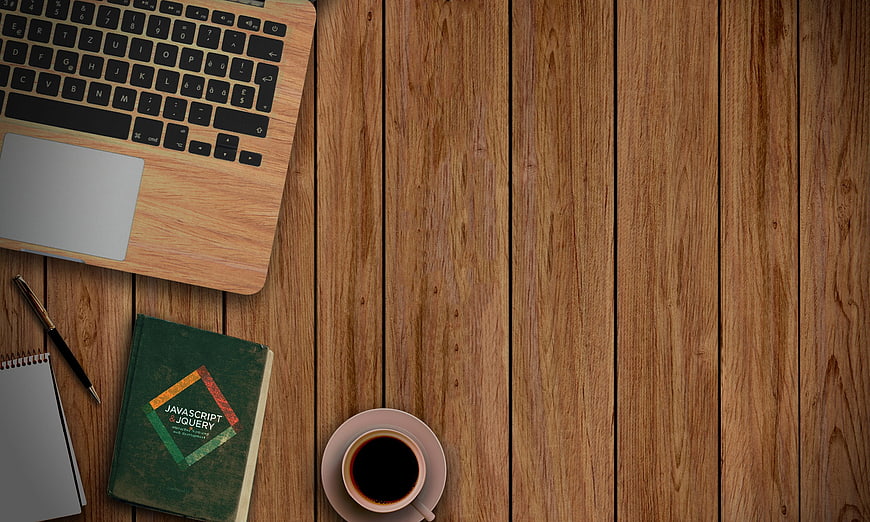 Flat lay of laptop, coding book, and coffee on wooden desk