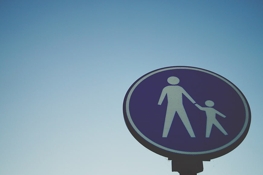 Blue Pedestrian Sign with Adult and Child Symbol Against Sky