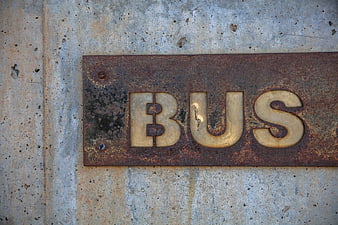 Rusty Metal Bus Sign on Concrete Wall
