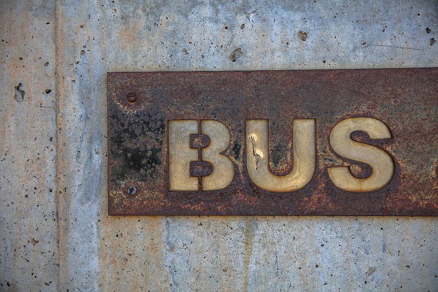Rusty Metal Bus Sign on Concrete Wall