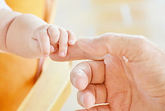 Close-up of baby hand holding adult finger