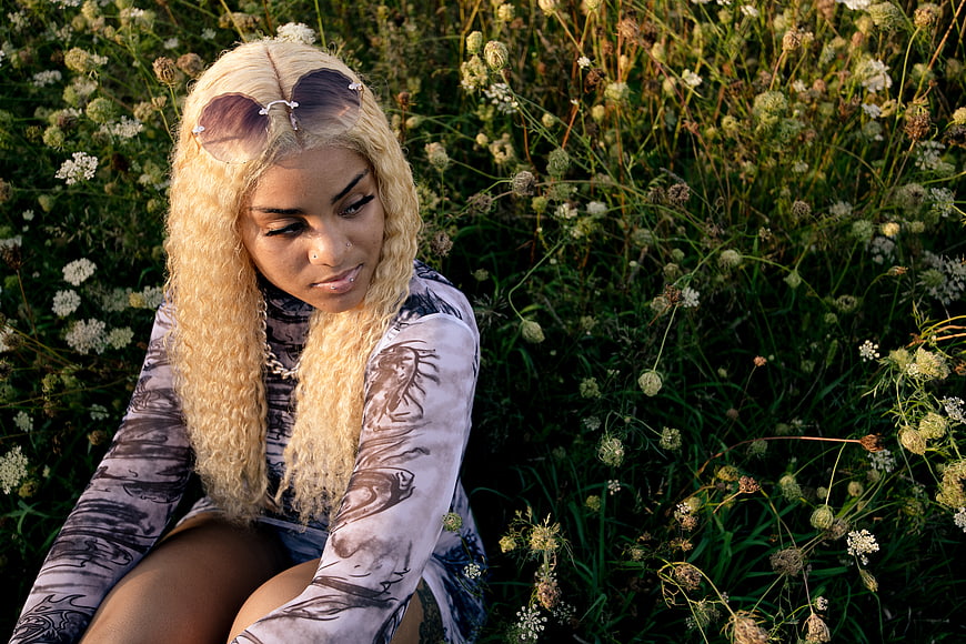 Blonde Woman with Sunglasses Sitting in Wildflower Field