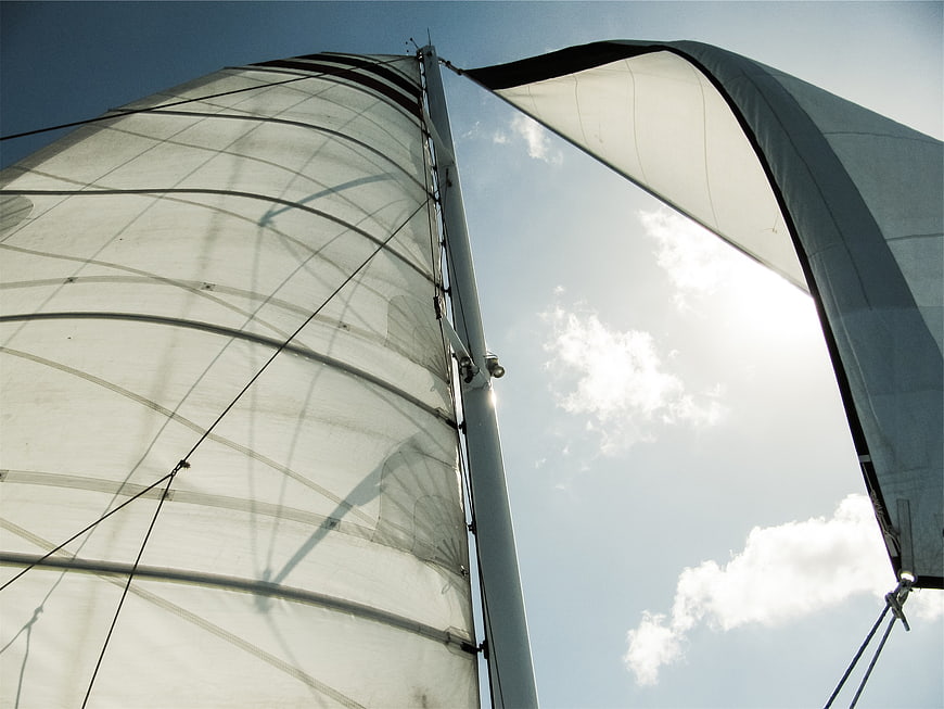 Low angle view of white sailboat sails against blue sky