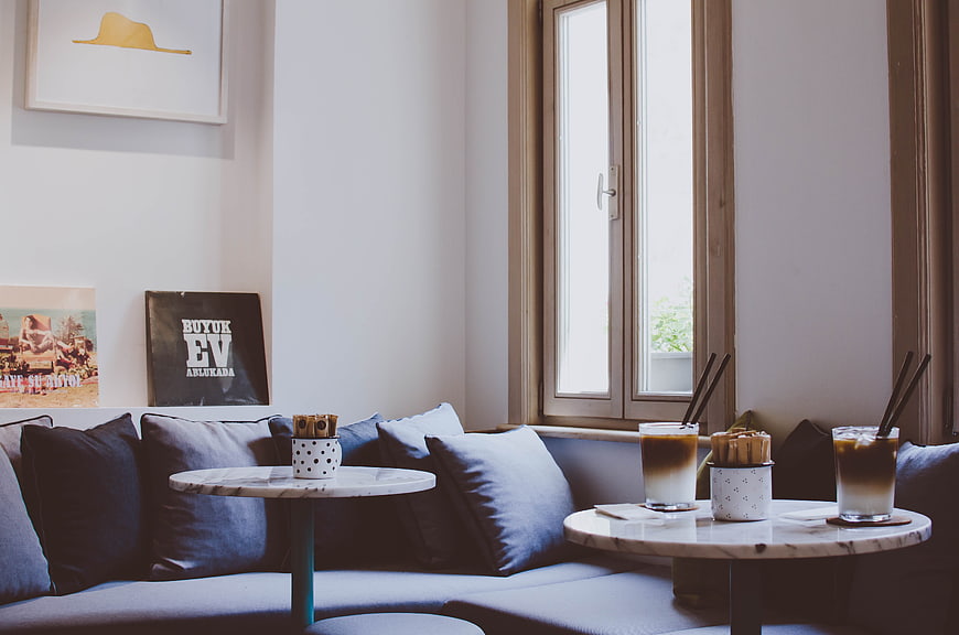 Cozy cafe interior with blue sofa, marble tables, and iced coffee drinks