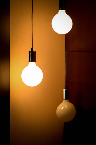 Three Hanging Pendant Light Bulbs Against Warm Background