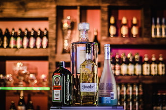 Assorted liquor bottles on a bar shelf with bokeh background