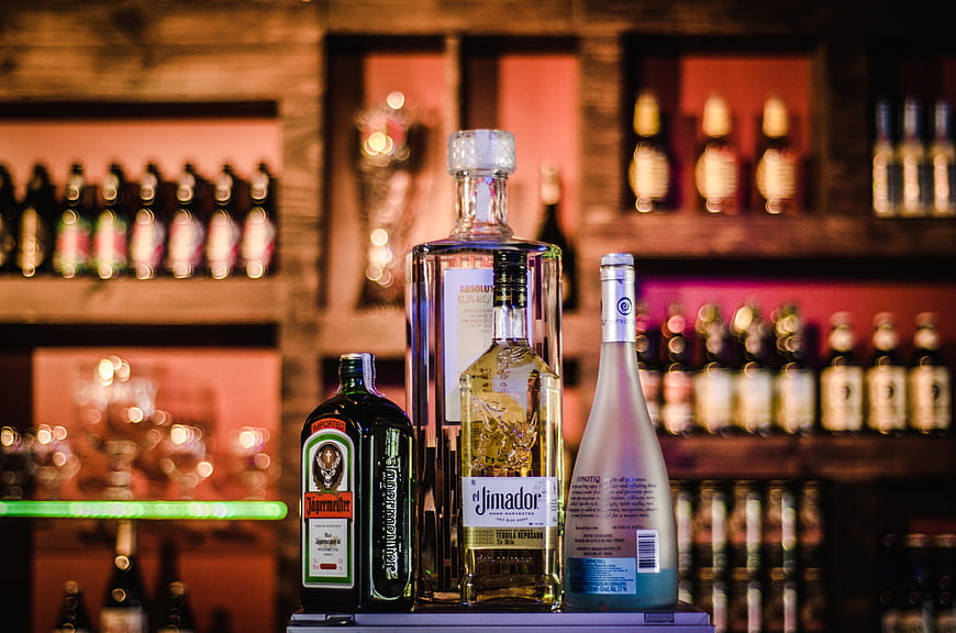 Assorted liquor bottles on a bar shelf with bokeh background