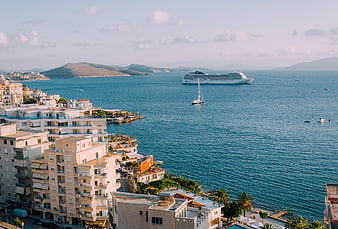 Coastal town view with cruise ship and sailing boat on the sea