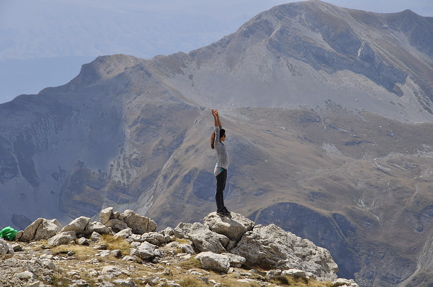 Woman standing on mountain peak with arms raised in victory