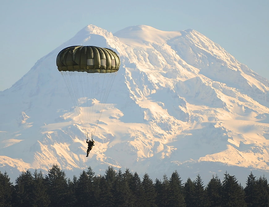 Skydiver landing with parachute against Mount Rainier