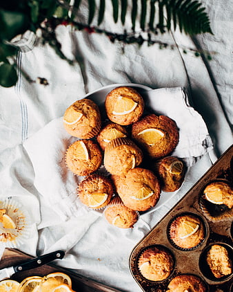 Overhead view of fresh orange muffins on white linen