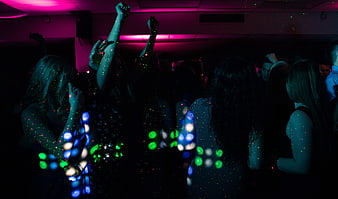 Crowd of people dancing at a dark nightclub with colorful laser lights