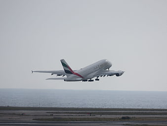 Emirates Airbus A380 taking off over ocean runway