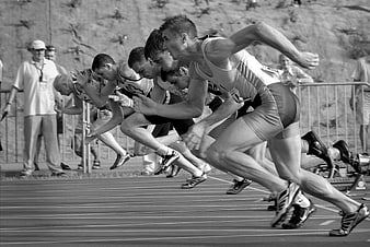 Black and white sprinters exploding from starting blocks