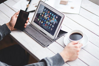 Person using tablet and smartphone with coffee on white table