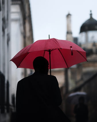 Silhouette of Man with Red Umbrella in Rainy City
