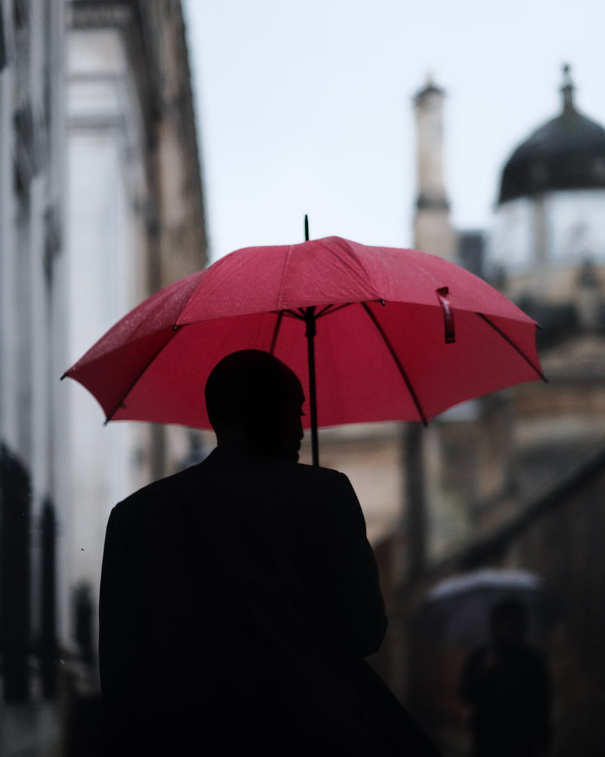 Silhouette of Man with Red Umbrella in Rainy City