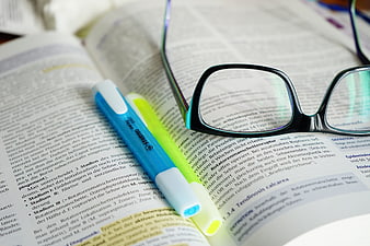 Reading glasses and highlighters on open textbook