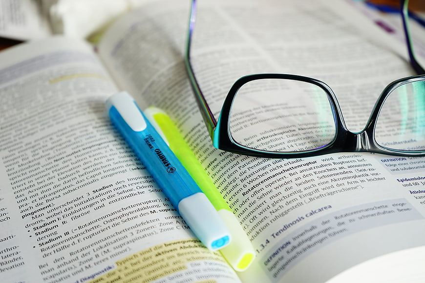 Reading glasses and highlighters on open textbook