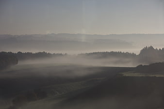 Misty autumn landscape with rolling hills and fog
