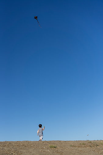 Child Flying Kite Against Blue Sky