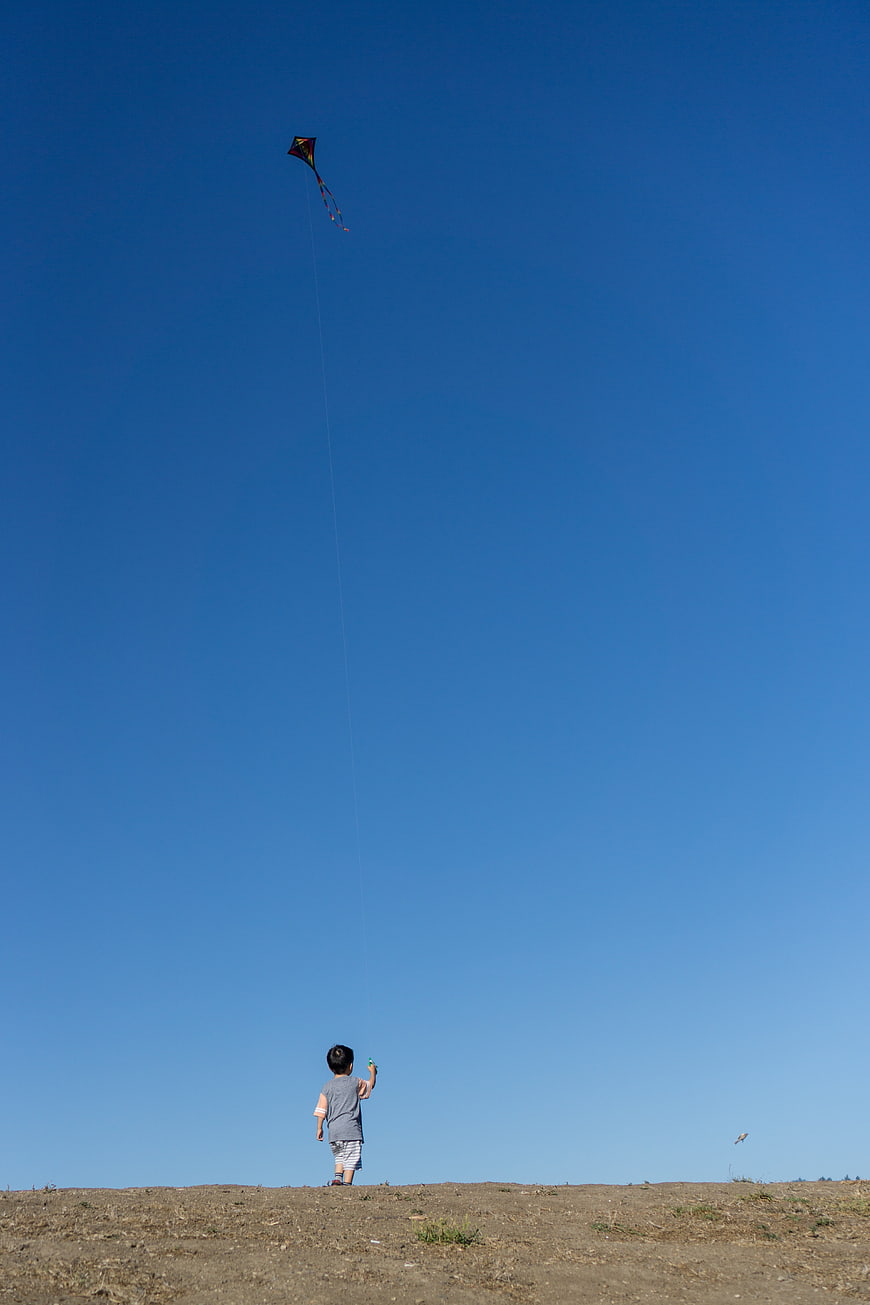 Child Flying Kite Against Blue Sky