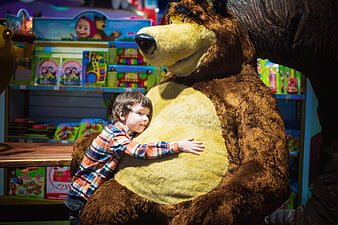 Young boy hugging large bear statue in toy store