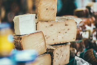 Assorted artisanal cheese wheels wrapped in plastic